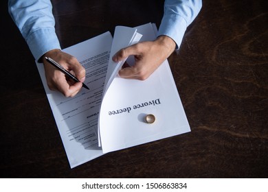 partial view of man sitting at table and signing divorce documents