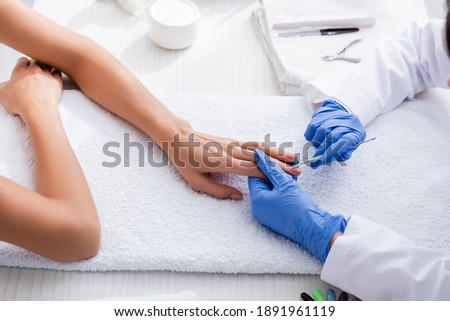 partial view of manicurist making manicure to woman with cuticle pusher