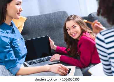 partial view of multicultural students with laptop