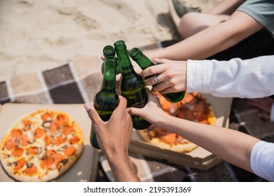 Partial View Of Multiethnic Friends Clinking Beer Bottles Near Tasty Pizza On Beach