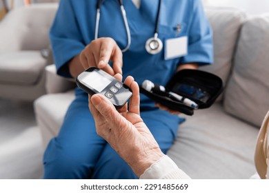 partial view of multiracial nurse pointing at glucometer in hand of senior woman - Powered by Shutterstock