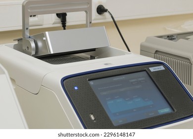 Partial view of a PCR instrument with an half open lid. Touch screen control panel. Science, laboratory equipment; technology