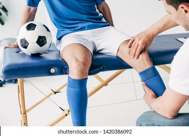 partial view of Physiotherapist massaging leg of football player in hospital