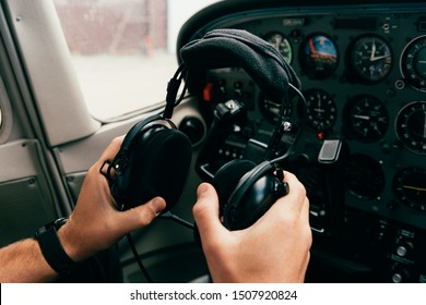 partial view of pilot in wristwatch holding headphones in plane