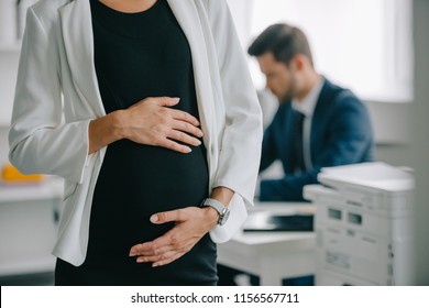 partial view of pregnant businesswoman and colleague at workplace in office - Powered by Shutterstock