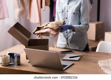 Partial View Of Proprietor In Latex Glove Packing Clothes Into Box In Showroom