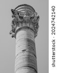 Partial view of the Roman column positioned at the end of the historic Via Appia in Brindisi, vertical image in black and white.
