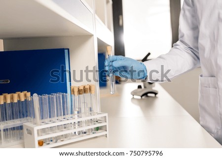 partial view of scientist in latex gloves holding test tube