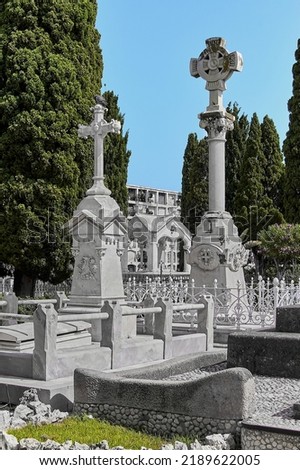 Partial view of Sitges cemetery with richly ornamented pantheons and niches in the background, as well as some very leafy trees under the blue sky for All Souls' Day, All Saints' Day and Halloween