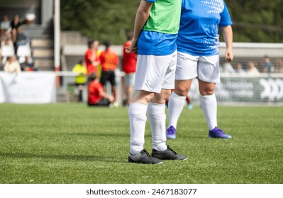 A partial view of a soccer player standing on a grass field with a focus on the legs and soccer cleats - Powered by Shutterstock