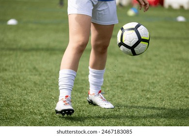 A partial view of a soccer player standing on a grass field with a focus on the legs and soccer cleats - Powered by Shutterstock