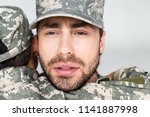 partial view of son hugging crying father in military uniform on grey background