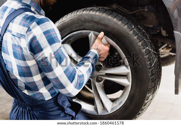 partial
view of technician fixing car wheel in
workshop