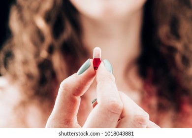 partial view of woman showing pill in hand