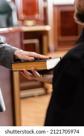 Partial View Of Woman Swearing On Bible Near Bailiff In Court