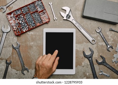 Partial view of worker using digital tablet on table with different carpentry tools 