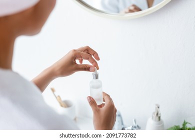 Partial View Of Young African American Woman Holding Bottle With Serum In Bathroom