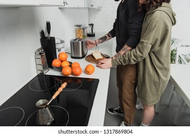 partial view of young couple preparing toasts together during breakfast in kitchen
