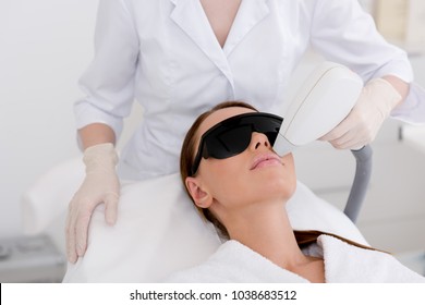 partial view of young woman receiving laser hair removal epilation on face in salon - Shutterstock ID 1038683512