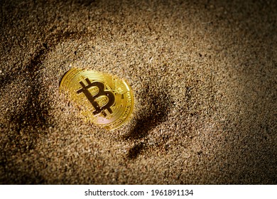 Partially Buried Bitcoin on sand with a vignette light.