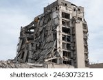 A partially collapsed building in an urban environment showing extensive damage and destruction. The image depicts the aftermath of a disaster or demolition.