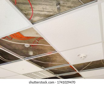 Partially Open Suspended Ceiling, With Plenum Area And Wires Visible Above Acoustic Panels And Fixtures