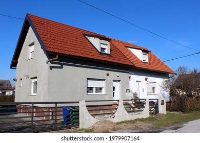 Partially Renovated Small Attached Suburban Family House With Two Entrances And Multiple New Windows Surrounded With Concrete And Metal Fence And Other Houses On Clear Blue Sky Background