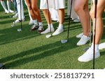 Participants line up with golf clubs on a lush green fairway during a sunny day at a golf tournament for amateur players