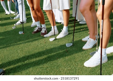 Participants line up with golf clubs on a lush green fairway during a sunny day at a golf tournament for amateur players - Powered by Shutterstock