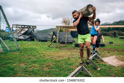 Participants in an obstacle course carrying trunks outdoors - Powered by Shutterstock