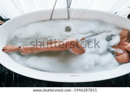 Particle view of legs. Beautiful young woman have free time at home in the bath.