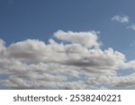 A partly cloudy sky with birds on a rooftop, A clear blue sky with white fluffy clouds, A partly cloudy sky. Light gray and white clouds