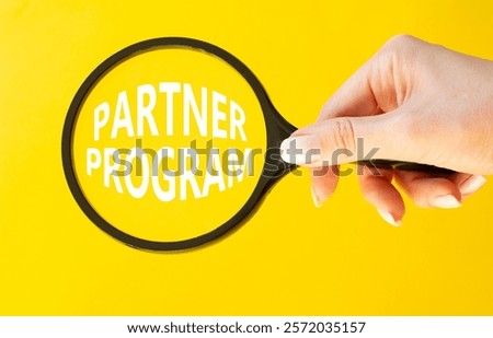 Partner Program symbol. Concept words Partner Program on magnifying glass. Businessman hand. Beautiful yellow background. Business and Partner Program concept. Copy space.