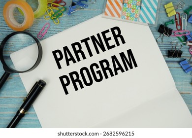 Partner Program text written on notepad with alarm clock and magnifying glass flat lay on wooden background