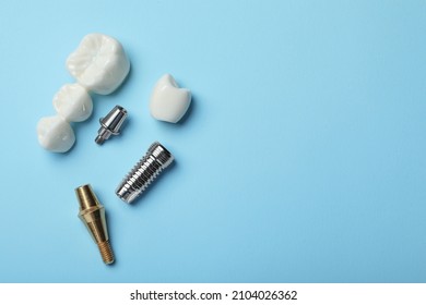 Parts of dental implant and bridge on light blue background, flat lay. Space for text - Shutterstock ID 2104026362