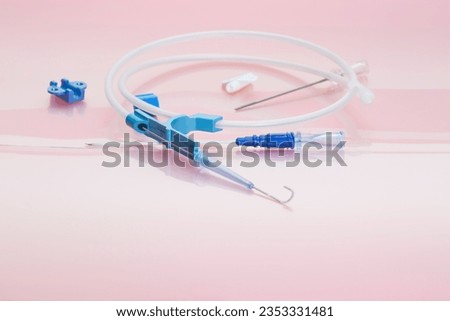 Parts of pressure injectable multi-lumen Peripherally Inserted Central Catheter kit with Vascular Access Guidewire, injection caps, filter needle and introducer needle on rose background 