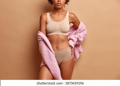 Parts of womans perfect body. Unrecognizable fitness female model in underwear and jumper has flat abdomen healthy skin good shape.