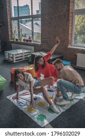 Party activities. Three friends playing active twister game at the party