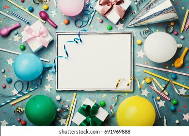 Party Or Birthday Background. Silver Frame With Colorful Balloon, Gift Box, Carnival Cap, Confetti, Candy And Streamer On Vintage Blue Table Top View. Flat Lay Style. Holiday Mockup.