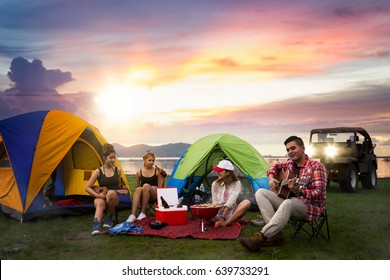 Party, Camping Of Asian Man And Women Group, Relaxing, Sing A Song And Cooking, With Ligh From Car And Tent