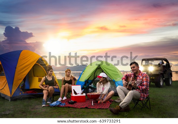 Party, Camping of\
asian man and women group, relaxing, sing a song and cooking, with\
ligh from car and tent
