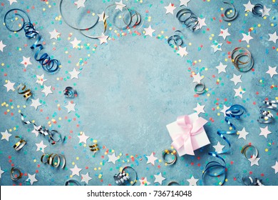 Party, Carnival Or Birthday Frame With Colorful Confetti, Gift Box And Streamer On Vintage Blue Table Top View. Flat Lay Style. Christmas Greeting Card With Copy Space.