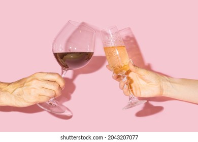 Party Cheers Concept. Two Hands, Man One Holding Glas Of Vine And Gilr Hand Holding Vintage Crystal Glasses With Lovely Drinks In It Against Baby Pink Background