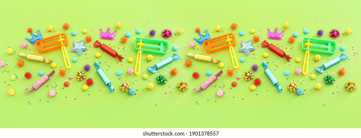 Party Colorful Confetti, Noise Maker And Candies Over Green Wooden Background . Top View, Flat Lay