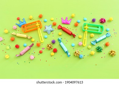 Party Colorful Confetti, Noise Maker And Candies Over Green Wooden Background . Top View, Flat Lay