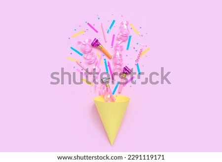 Party cone with confetti and whistles on pink background. Children's Day celebration