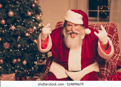 It's Party! Cool Santa Claus Showing Tongue Out And Gesturing With Fingers Rock-and-roll Near Christmas Tree At Home