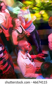 Party Crowd On A Busy Dance Floor, Engulfed In The Lights Of A Nightclub