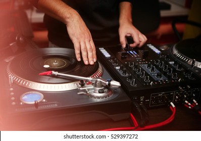 Party dj plays music at hip hop concert on turntables vinyl record player & sound mixer.Retro analog audio equipment for disc jockey scratching vinyls records.Retro djs stage equipment on party stage