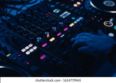 Party Dj Plays Music.Professional Disc Jockey Mixes Musical Tracks At Techno Party In Dark Blue Lights.Overhead View On Sound Mixer Panel And Cd Players Turntables With Illuminated Buttons